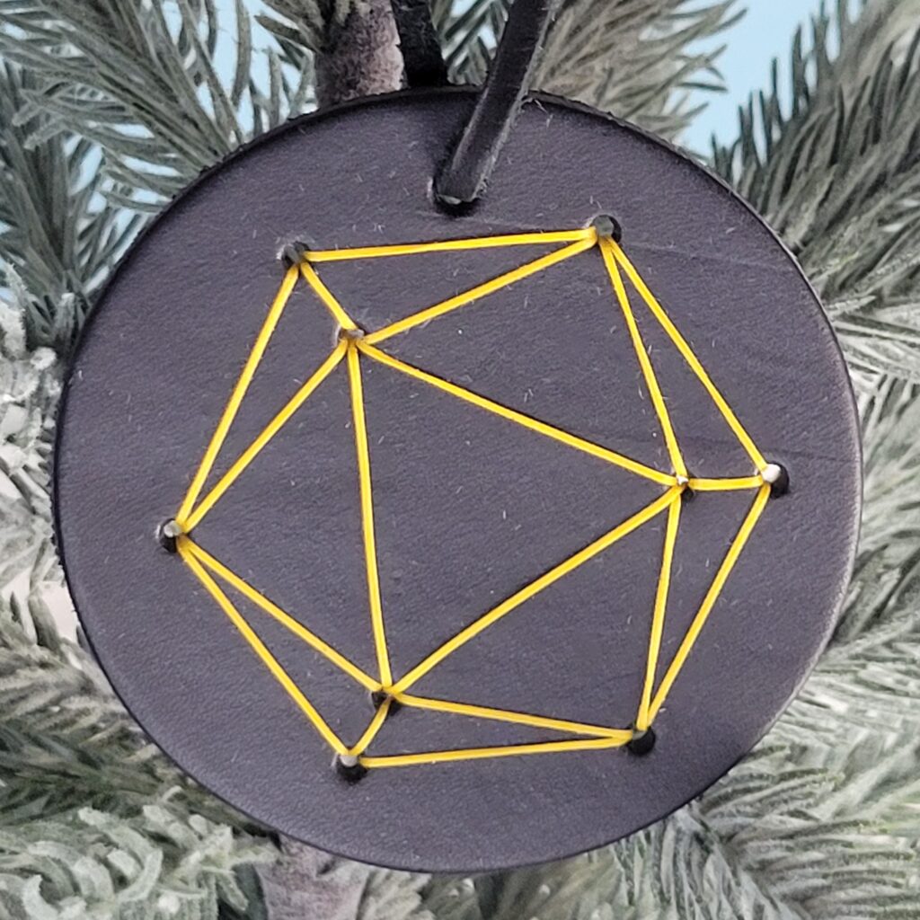 D20 Dice ornament. A black circle with a yellow dice stitched on front. The yellow is just the outline of of a D20 dice.
